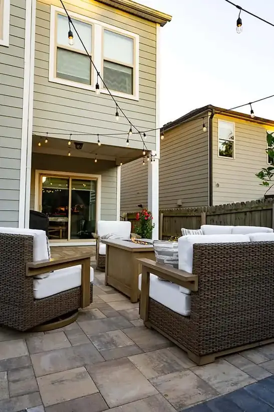 Paver patio with lounge seating under string lights at dusk